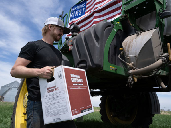 Farmer carrying a box of Willowood Sulfen Met